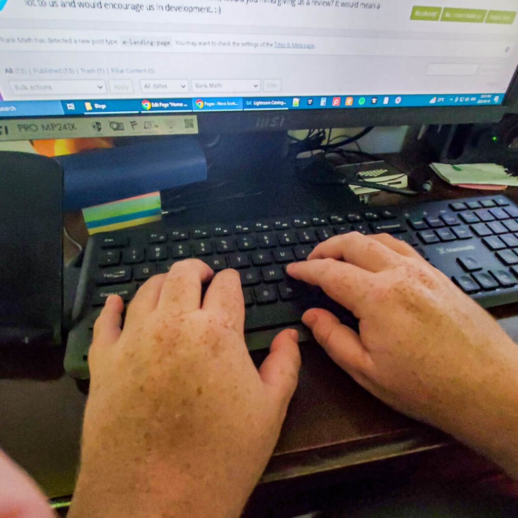 my hands typing on keyboard with partial monitor above displaying WordPress